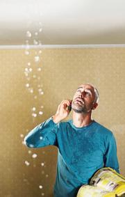 Customer looks at leaking ceiling while calling a Herndon plumbing company